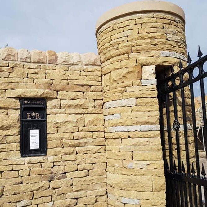 Dry stone wall and pillar with black mental gate